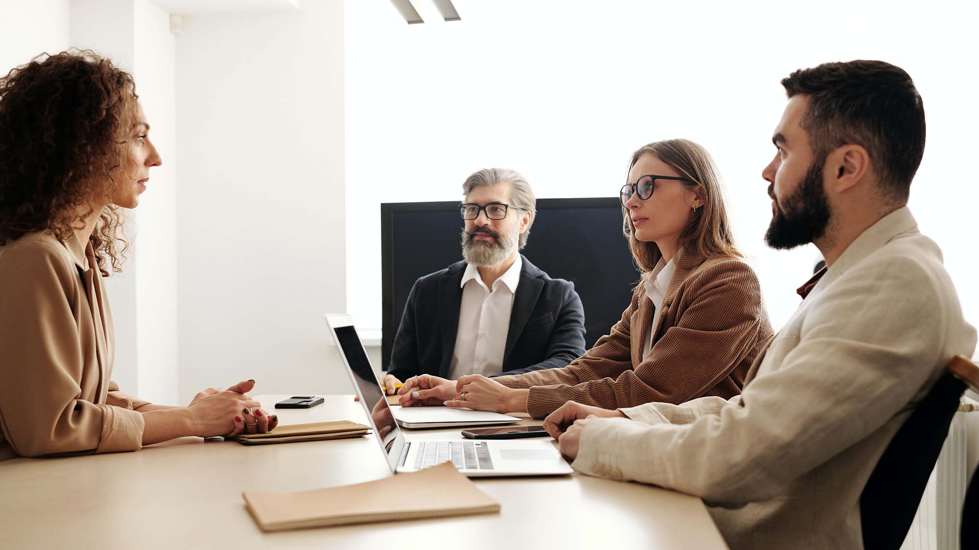 large image of 4 people sitting together at a desk